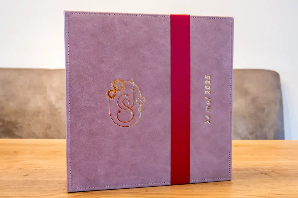 Luxe trouwalbum met paarse leren omslag, goudfolie en rood lint – geleverd door bruidsfotograaf Daniël Vos op 24 mei 2025